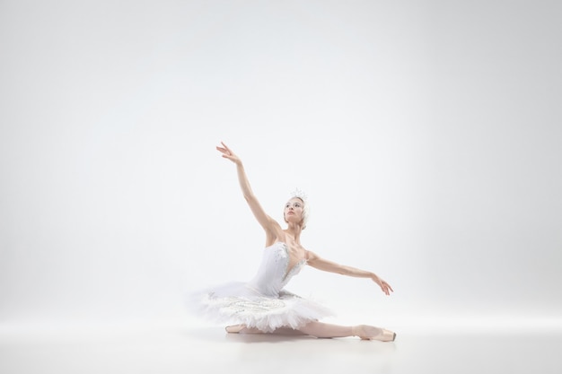 Danse de ballerine classique gracieuse isolée sur fond de studio blanc. Femme en vêtements tendres comme un cygne blanc. Le concept de grâce, d'artiste, de mouvement, d'action et de mouvement. Ça a l'air en apesanteur.