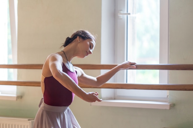 Danseur de ballet classique posant à la barre dans la salle de répétition