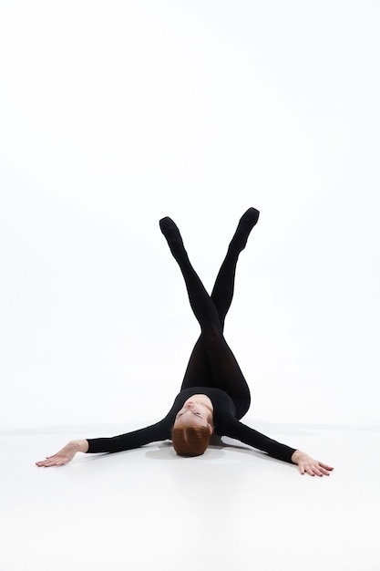 Danseur de ballet jeune et gracieux dans un style noir minimal isolé sur fond de studio blanc.