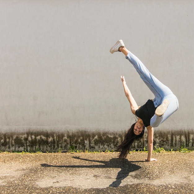 Danseur hip-hop souriant pose devant le mur gris