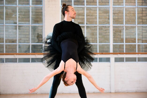 Danseur plein coup tenant la ballerine