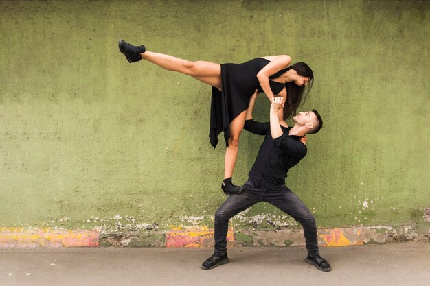 Danseur Tango portant une femme en robe noire sur ses genoux