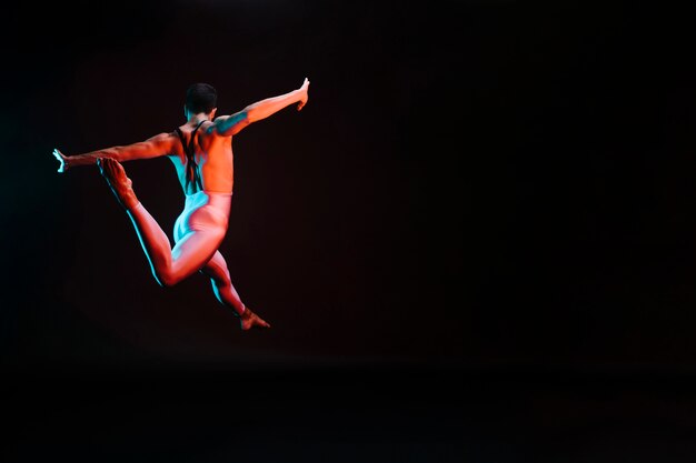 Danseuse de ballet méconnaissable sautant avec les bras écartés et se dédoublant