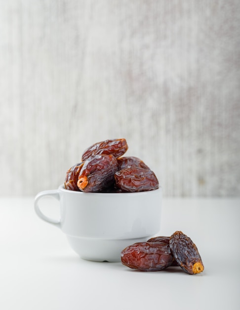 Dates dans une tasse blanche sur grunge et tableau blanc. vue de côté.