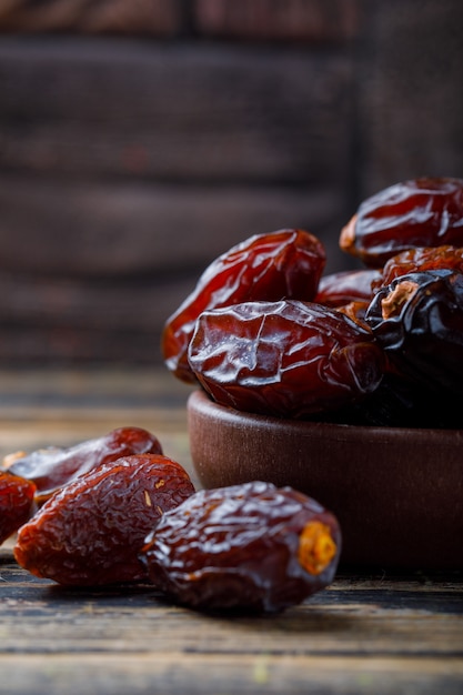 Photo gratuite dates sucrées dans une assiette d'argile sur carreaux de pierre et fond en bois, gros plan.