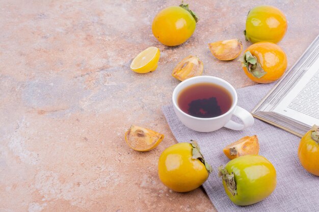 Dattes de prune jaune et tranches de citron avec une tasse de thé.