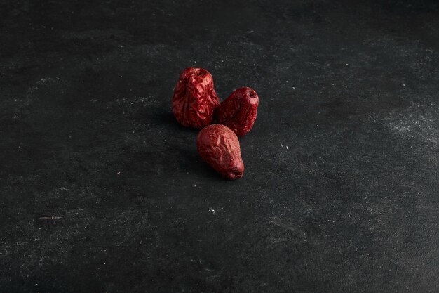 Dattes sèches rouges isolées sur une surface noire.