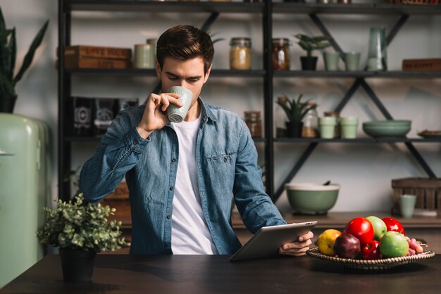 Debout, cuisine, boire café, tenue, tablette numérique