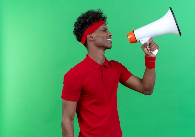 Photo gratuite debout en vue de profil jeune homme sportif portant un bandeau et un bracelet parle