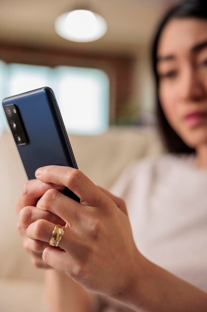 Décontracté authentique femme asiatique heureuse à l'aide d'un smartphone à la maison, technologie Internet Web utilisateur de smartphone message mobile appareil numérique de communication sur les médias sociaux