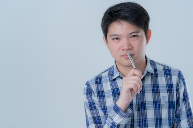 Décontracté décontracté homme intelligent asiatique pensant avec un stylo et une note papier avec bonheur sourire fond blanc
