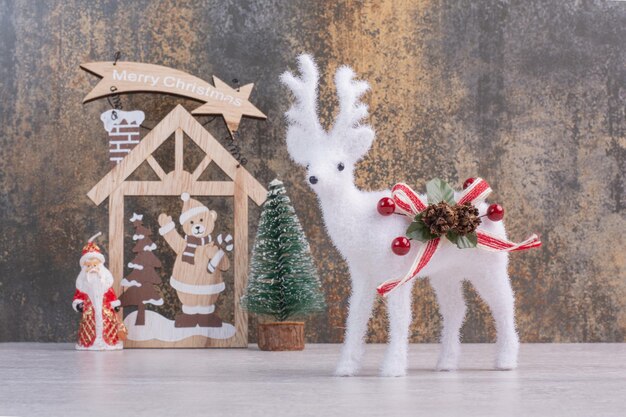 Décoration en bois de Noël et jouet de cerf sur une surface blanche.