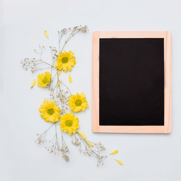 Décoration de fleur jaune près de l&#39;ardoise vierge en bois sur fond blanc