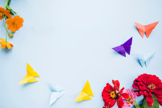 Décoration avec des fleurs de calendula et des papillons en papier origami sur fond bleu