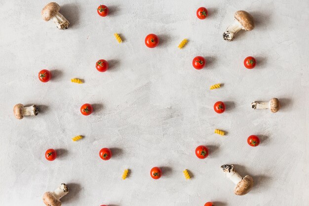 Décoration de légumes et de fusilli dans un cadre circulaire sur fond blanc