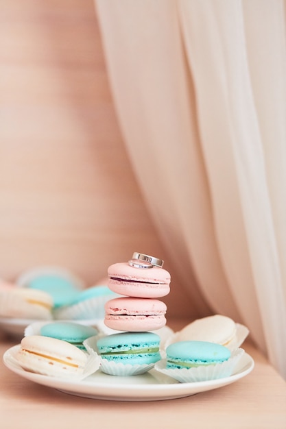 Décoration de mariage. Des bagues classiques en or blanc reposent sur des macarons roses et à la menthe