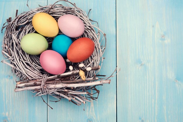 Décorations de Pâques multicolores sur la planche bleu pastel