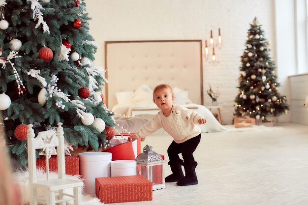 Décorations de vacances d&#39;hiver. Couleurs chaudes. Belle petite fille joue avec des boîtes à cadeaux