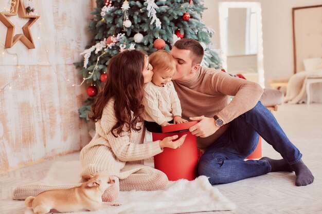 Décorations de vacances d&#39;hiver. Couleurs chaudes. Maman, papa et petite fille jouent avec un chien