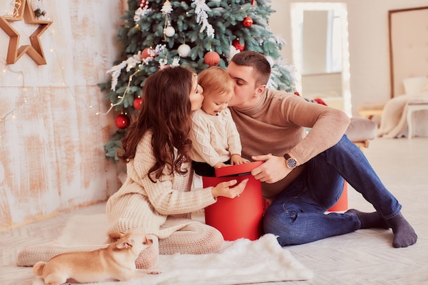 Décorations de vacances d&#39;hiver. Couleurs chaudes. Maman, papa et petite fille jouent avec un chien