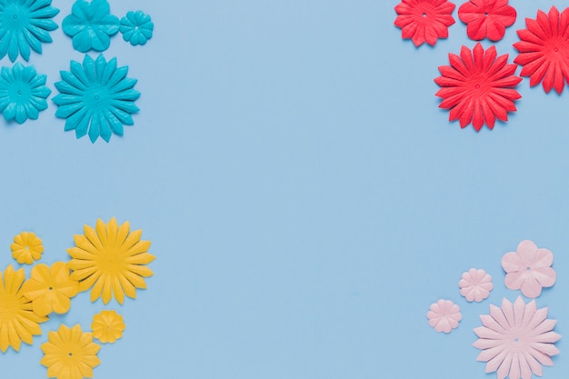 Photo gratuite découpe de fleurs décoratives colorées au coin du fond bleu