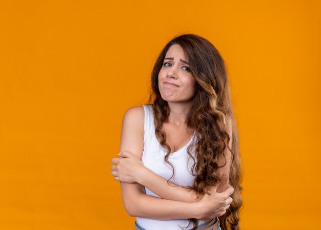 Déçu jeune belle fille debout avec une posture fermée sur un espace orange isolé avec copie espace