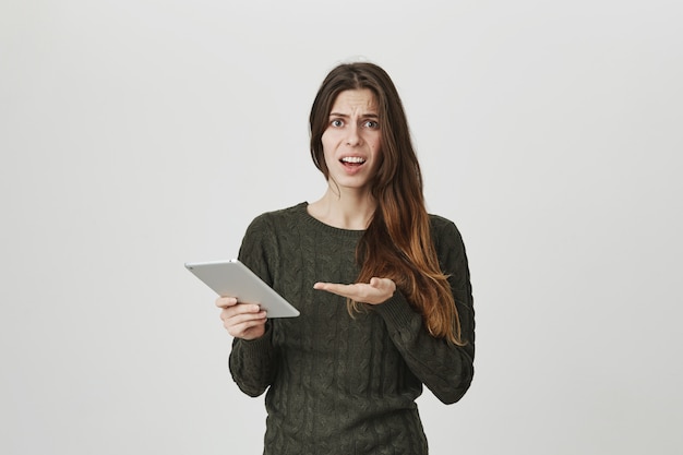 Déçu jeune femme séduisante se plaignant de quelque chose dans la tablette numérique