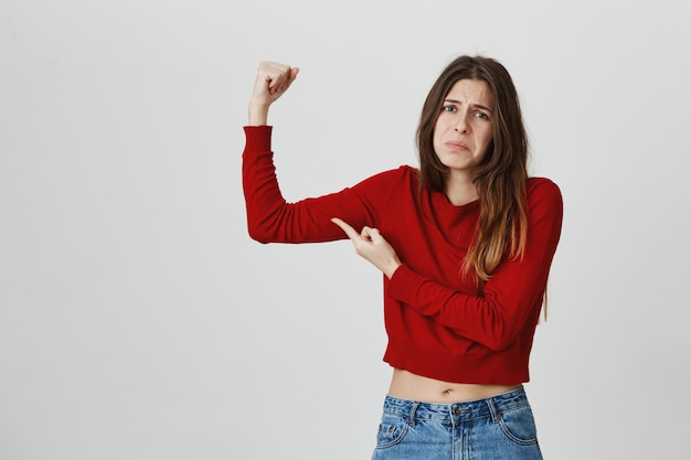 Photo gratuite déçu jolie fille flex biceps et grimaçant, sensation de semaine, besoin d'acheter un abonnement à une salle de sport