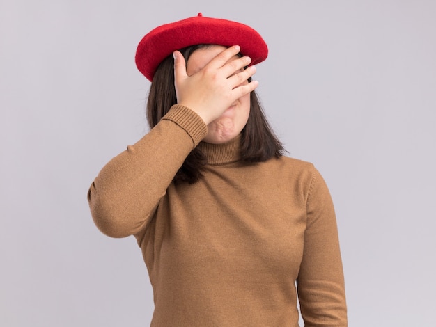 Photo gratuite déçue jeune jolie fille caucasienne avec un chapeau de béret couvre le visage avec la main isolée sur un mur blanc avec espace de copie