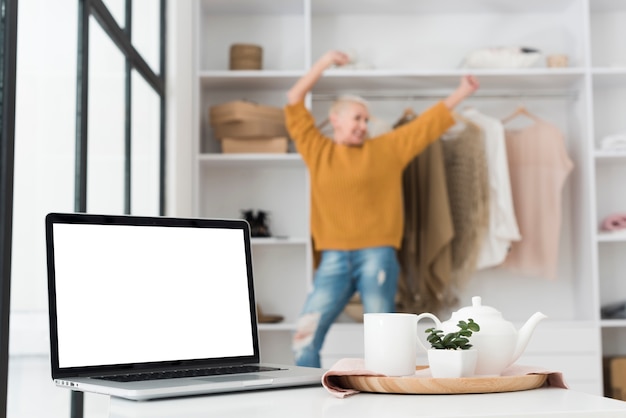 Défocalisé femme aînée avec ordinateur portable et service à thé