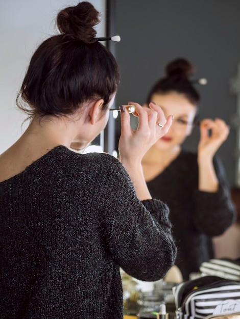 Photo gratuite défocalisé femme appliquant le mascara vue arrière