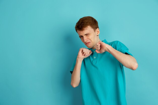 Dégoûté, en colère. Portrait moderne du jeune homme caucasien isolé sur mur bleu, monochrome. Beau modèle masculin. Concept d'émotions humaines, expression faciale, ventes, publicité, tendance.