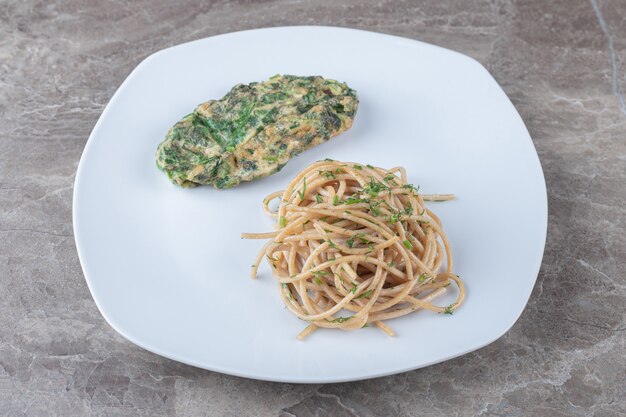 Délicieuse Côtelette D'oeufs Avec Des Verts Et Des Spaghettis Sur Une Assiette Blanche. Photo gratuit