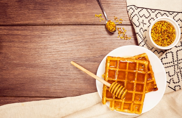 Délicieuse gaufre belge au miel et au pollen d'abeille sur un bureau en bois