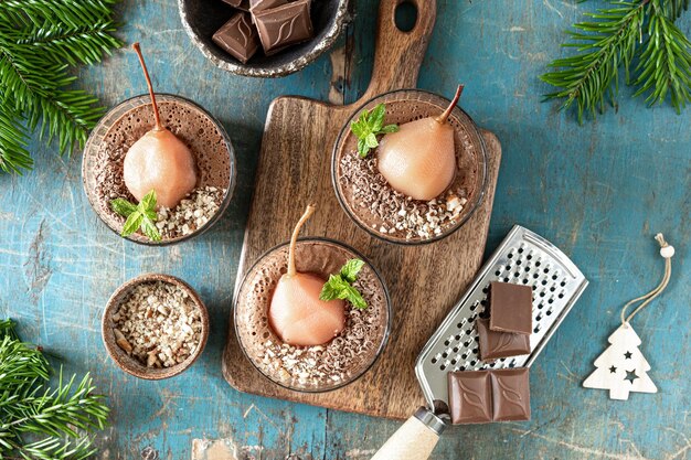 Délicieuse mousse au chocolat avec poires pochées dans des cadres en verre sur une table en bois bleue