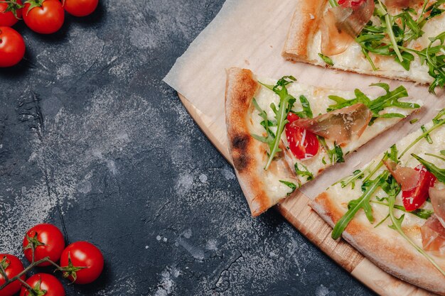 Délicieuse pizza napolitaine à bord avec des tomates cerises, espace libre pour le texte