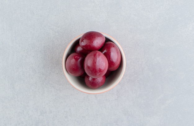 Délicieuse prune marinée dans un bol sur la surface en marbre