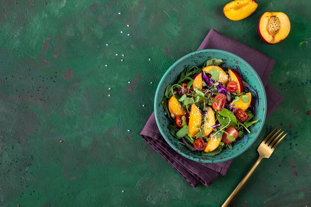 Délicieuse salade d'été avec du fromage burrata et des pêches grillées, de la roquette et des micropousses. Alimentation équilibrée. espace de copie