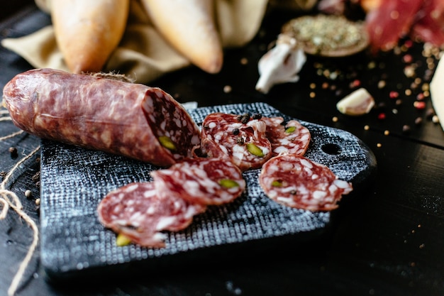 Délicieuse saucisse italienne tranchée aux pistaches et aux épices sur une planche à découper noire