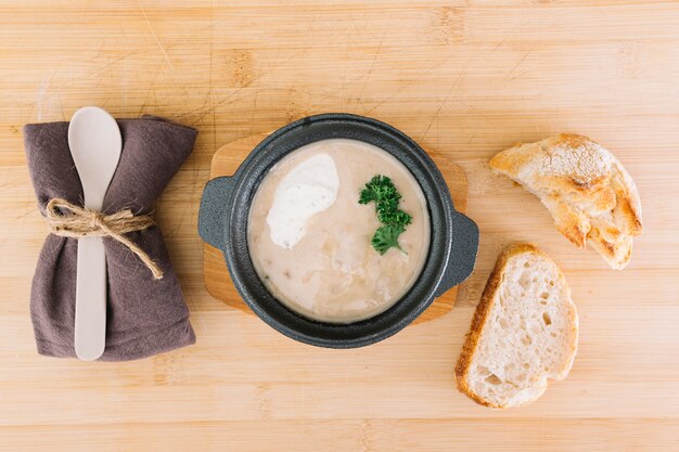 Délicieuse soupe aux champignons avec des tranches de pain; serviette et cuillère sur une table en bois
