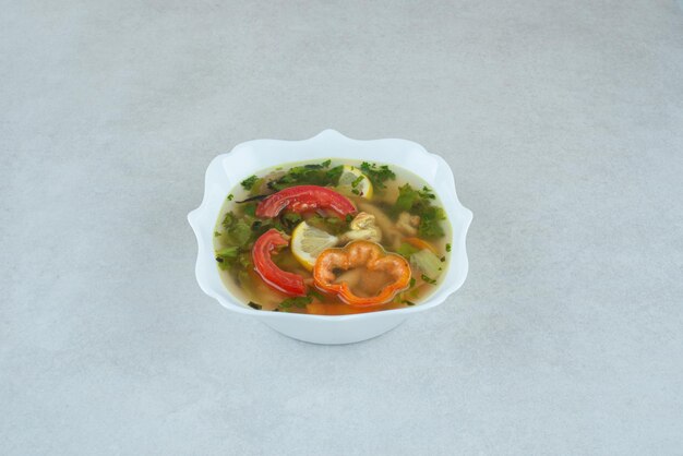 Délicieuse soupe aux légumes verts et poivrons dans une assiette blanche.