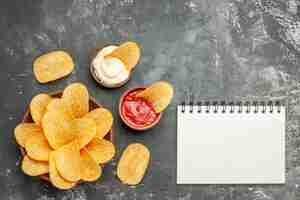 Photo gratuite de délicieuses croustilles mayonnaise maison avec du ketchup et de l'ordinateur portable sur table grise