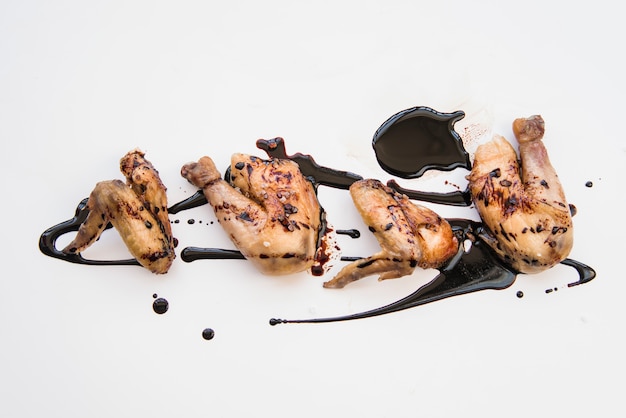 Délicieuses cuisses de poulet rôties et ailes de poulet garnies de sauce soja sur fond blanc