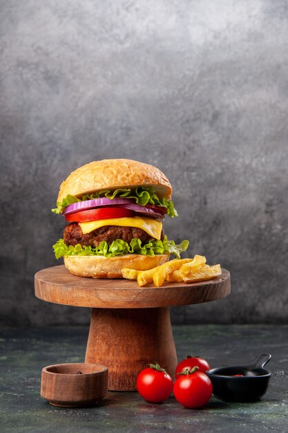 Délicieuses frites sandwich sur planche de bois tomates ketchup poivre sur surface de couleur sombre