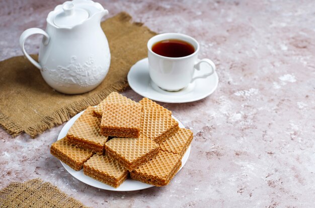 De délicieuses gaufrettes et une tasse de café pour le petit déjeuner sur fond clair, vue de dessus