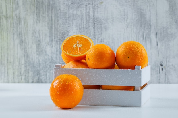 Délicieuses Oranges Avec Des Gouttes Dans Une Boîte En Bois Blanche Sur Un Mur Gris Blanc Et Grungy, Vue Latérale.