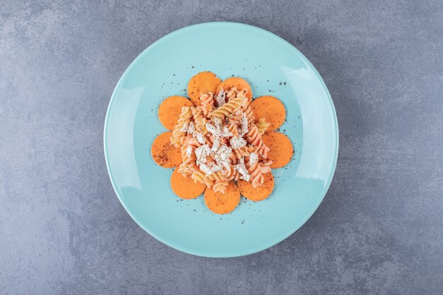 Délicieuses pâtes fusilli et carottes sur plaque bleue.