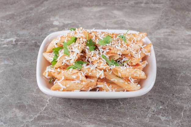 Délicieuses pâtes penne dans le bol, sur la surface en marbre.