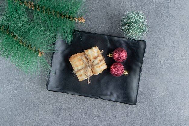 Délicieuses pâtisseries avec des boules de Noël sur une assiette sombre