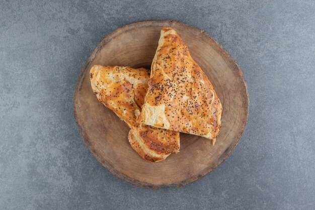 Délicieuses pâtisseries remplies de viande sur pièce en bois.